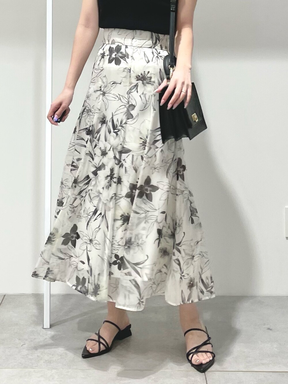 ブラック系のニット/セーター、ホワイト系のスカート、ブラック系のサンダルを着用したレディースの春コーディネートの4枚目の写真