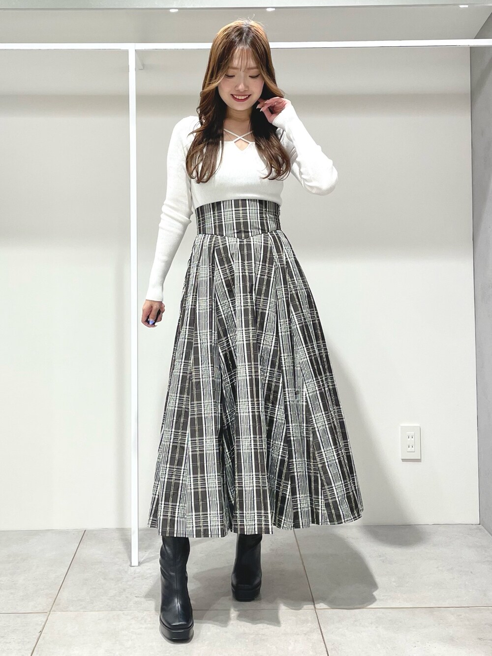 ブラック系のスカート、ブラック系のブーツ、ホワイト系のニット/セーターを着用したレディースの秋コーディネートの6枚目の写真