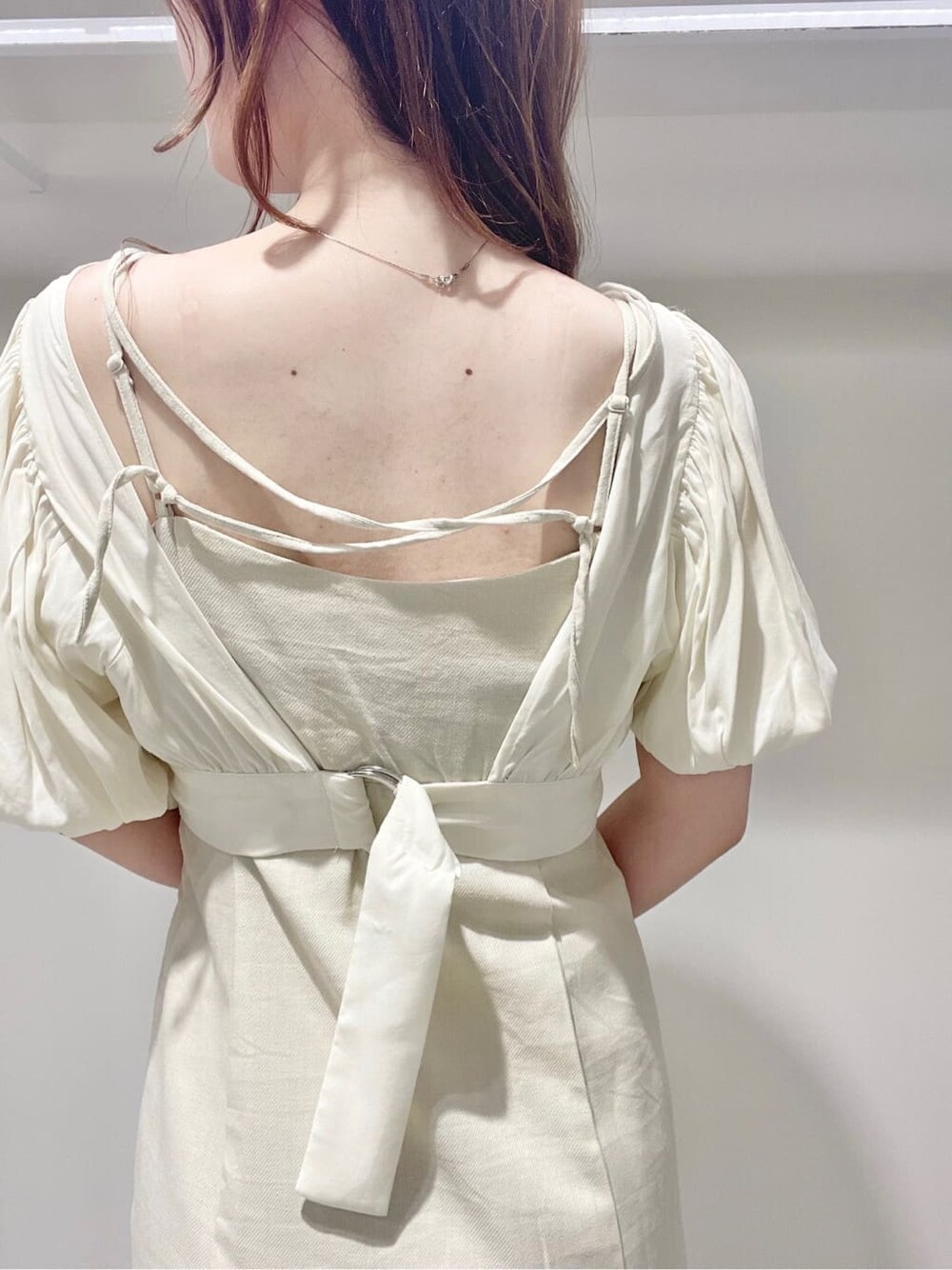 ベージュ系のサンダル、ベージュ系のトートバッグ、ホワイト系のワンピースを着用したレディースの春コーディネートの5枚目の写真