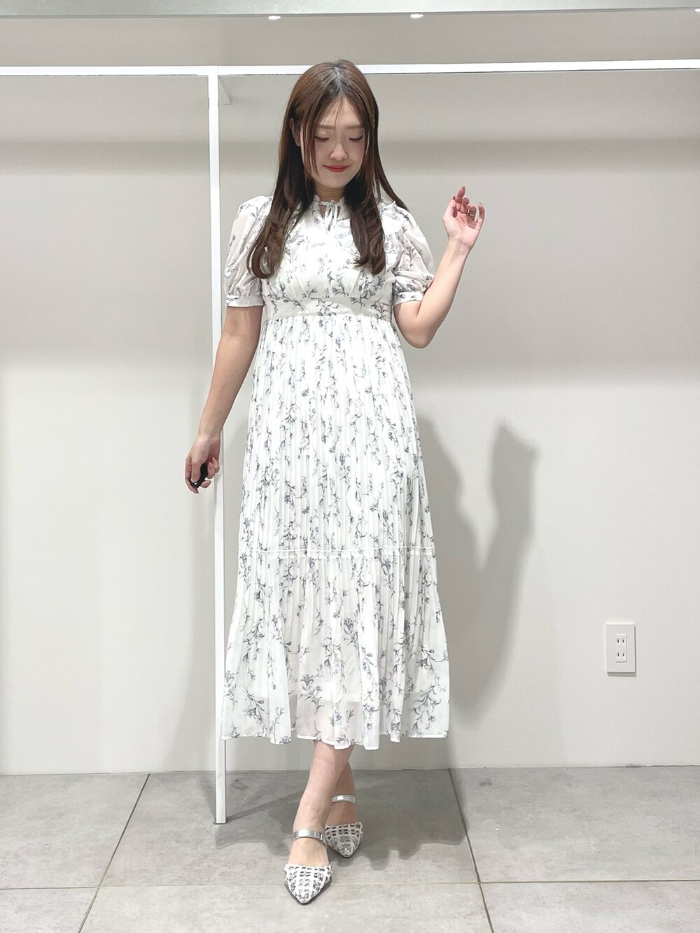 ホワイト系のトレンチコート、ホワイト系のワンピース、シルバー系のパンプスを着用したレディースの春コーディネートの4枚目の写真