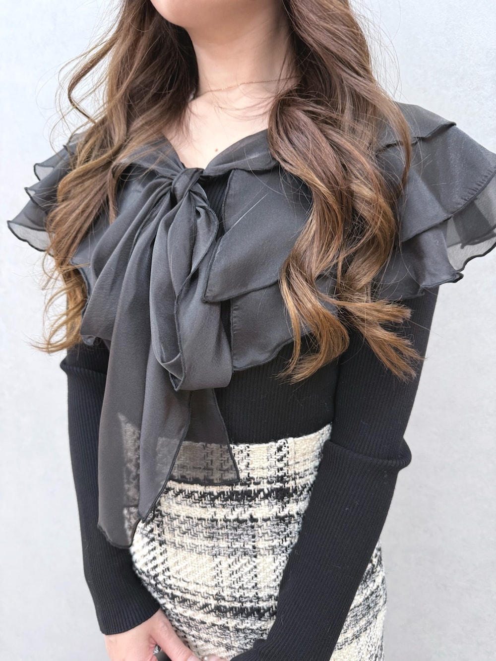 ブラック系のニット/セーター、ホワイト系のスカート、ブラック系のブーツを着用したレディースの冬コーディネートの4枚目の写真