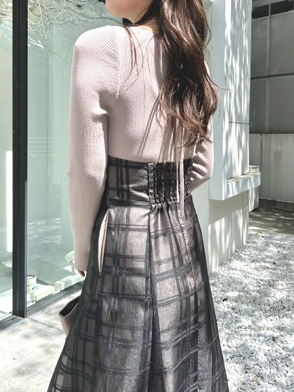 ピンク系のワンピース、ベージュ系のハンドバッグ、ホワイト系のライダースジャケットを着用したレディースの秋コーディネートの9枚目の写真