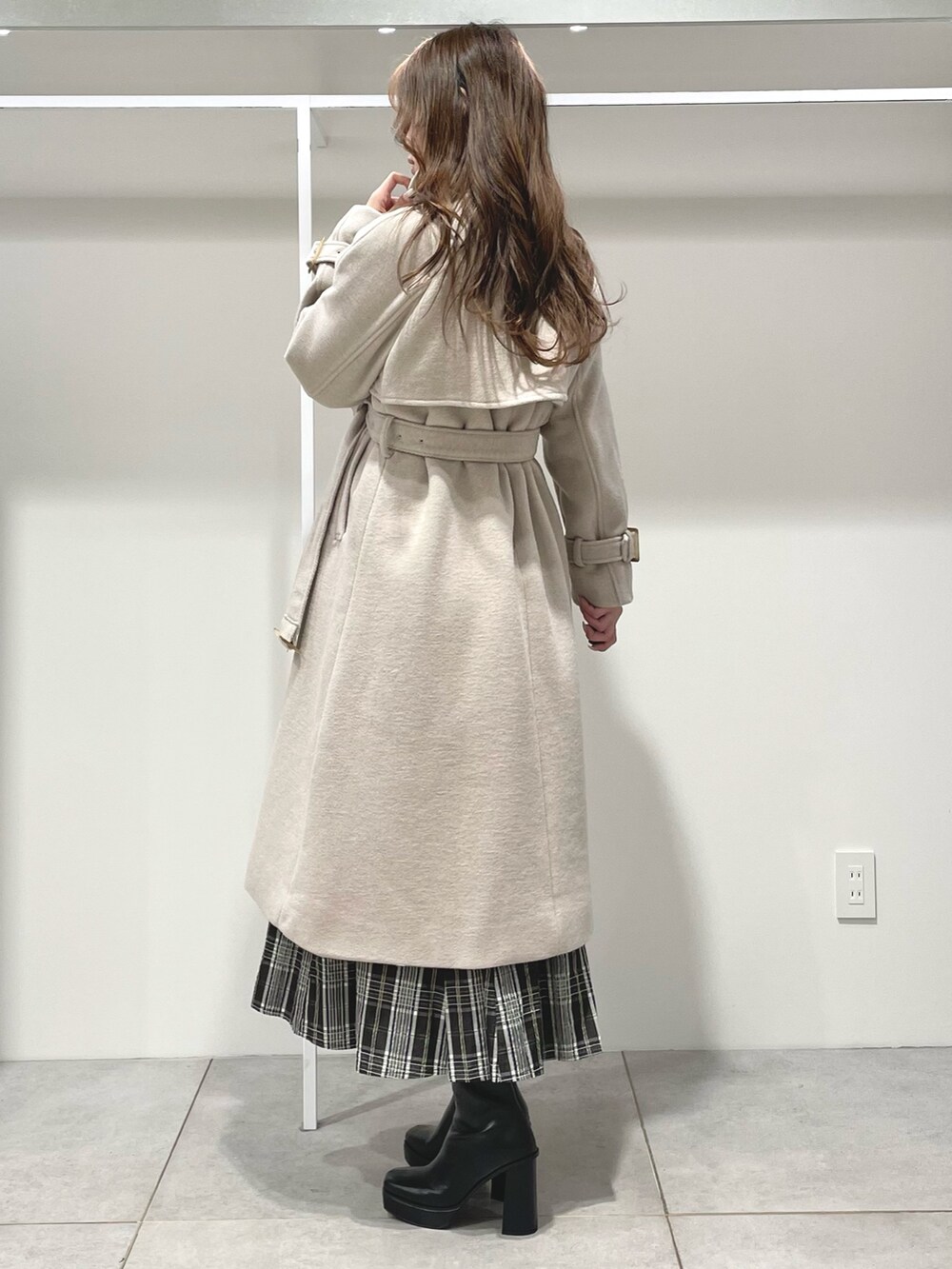 ブラック系のスカート、ブラック系のブーツ、ホワイト系のニット/セーターを着用したレディースの秋コーディネートの3枚目の写真