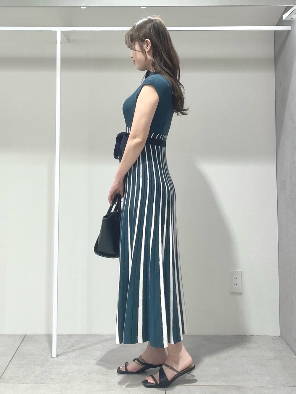 ブラック系のトートバッグ、ブラック系のサンダル、グリーン系のワンピースを着用したレディースの夏コーディネートの2枚目の写真