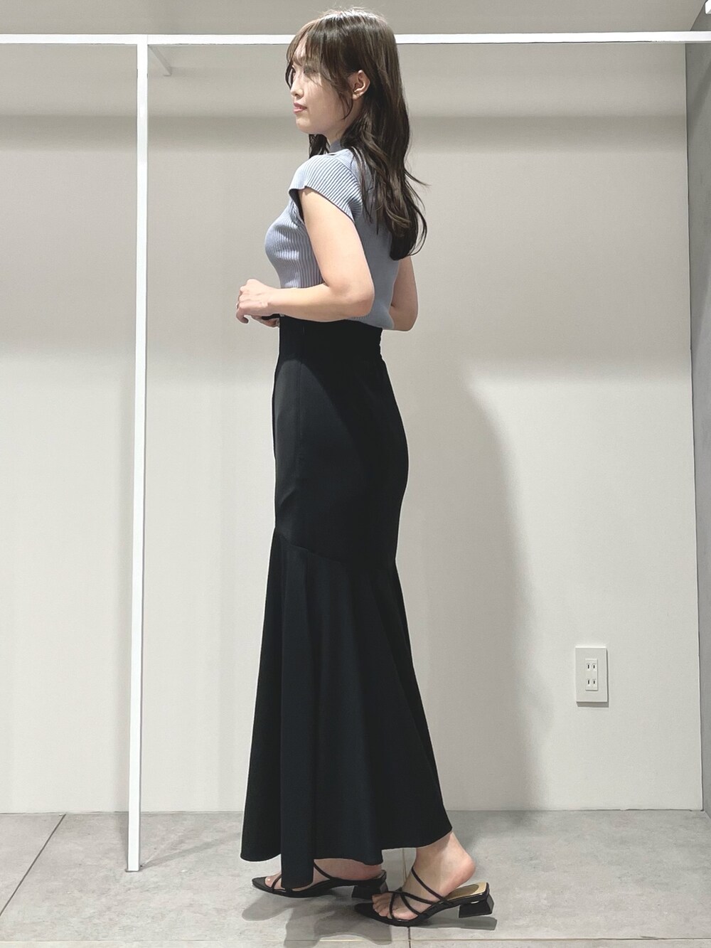 ブルー系のニット/セーター、ブラック系のスカート、ブラック系のサンダルを着用したレディースの夏コーディネートの3枚目の写真