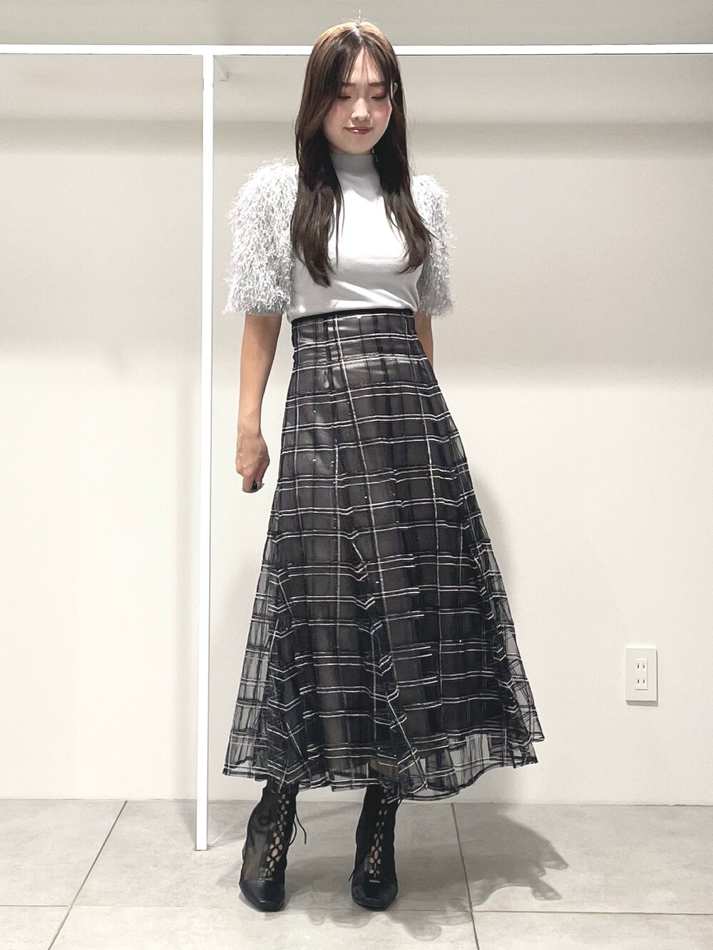 グレー系のニット/セーター、ブラック系のハンドバッグ、ブラック系のスカートを着用したレディースの秋コーディネートの2枚目の写真