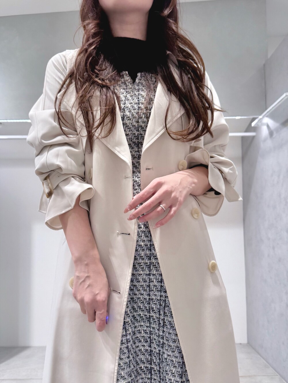 ホワイト系のトレンチコート、ブラック系のワンピース、ブラック系のブーツを着用したレディースの冬コーディネートの5枚目の写真