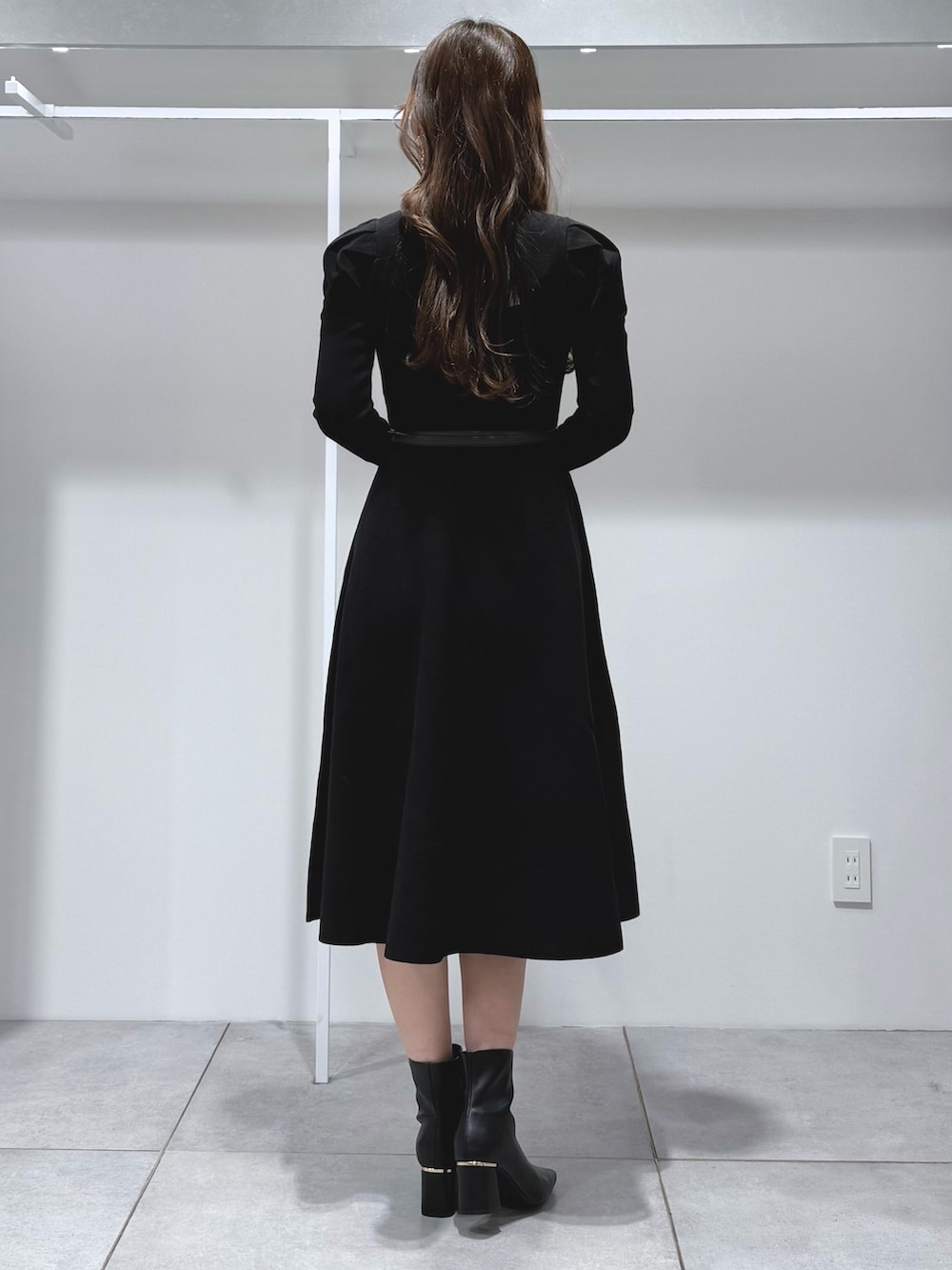 ホワイト系のハンドバッグ、ブラック系のブーツ、ブラック系のワンピースを着用したレディースの冬コーディネートの4枚目の写真