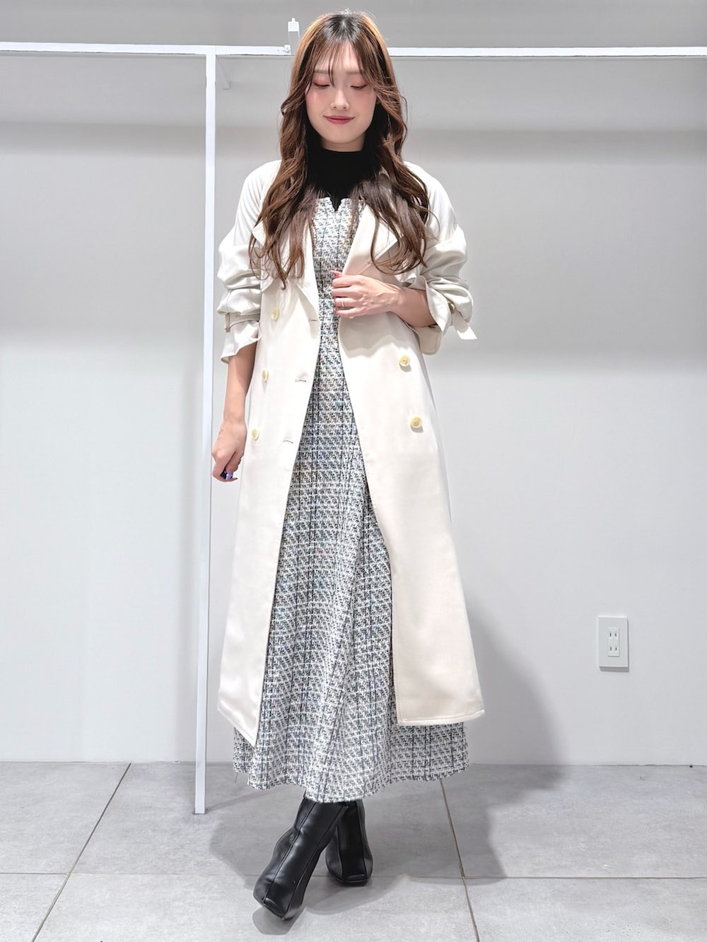 ホワイト系のトレンチコート、ブラック系のワンピース、ブラック系のブーツを着用したレディースの冬コーディネートの2枚目の写真