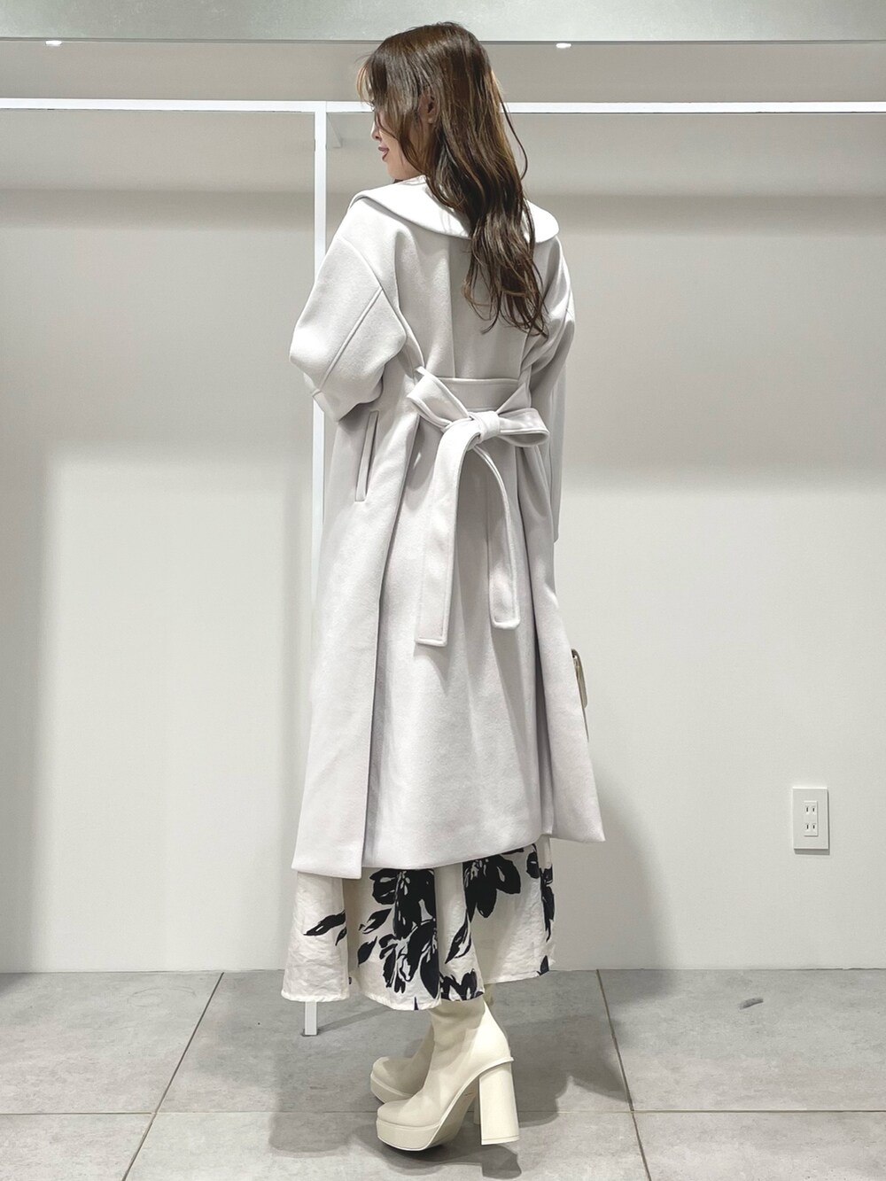 ホワイト系のスカート、ホワイト系のチェスターコート、ベージュ系のカーディガン/ボレロを着用したレディースの秋コーディネートの2枚目の写真