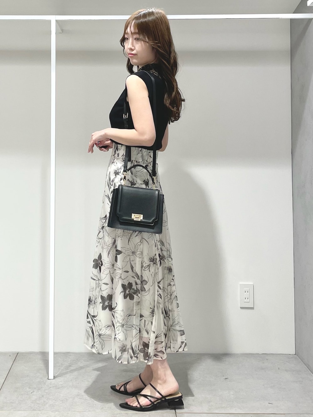 ブラック系のニット/セーター、ホワイト系のスカート、ブラック系のサンダルを着用したレディースの春コーディネートの2枚目の写真