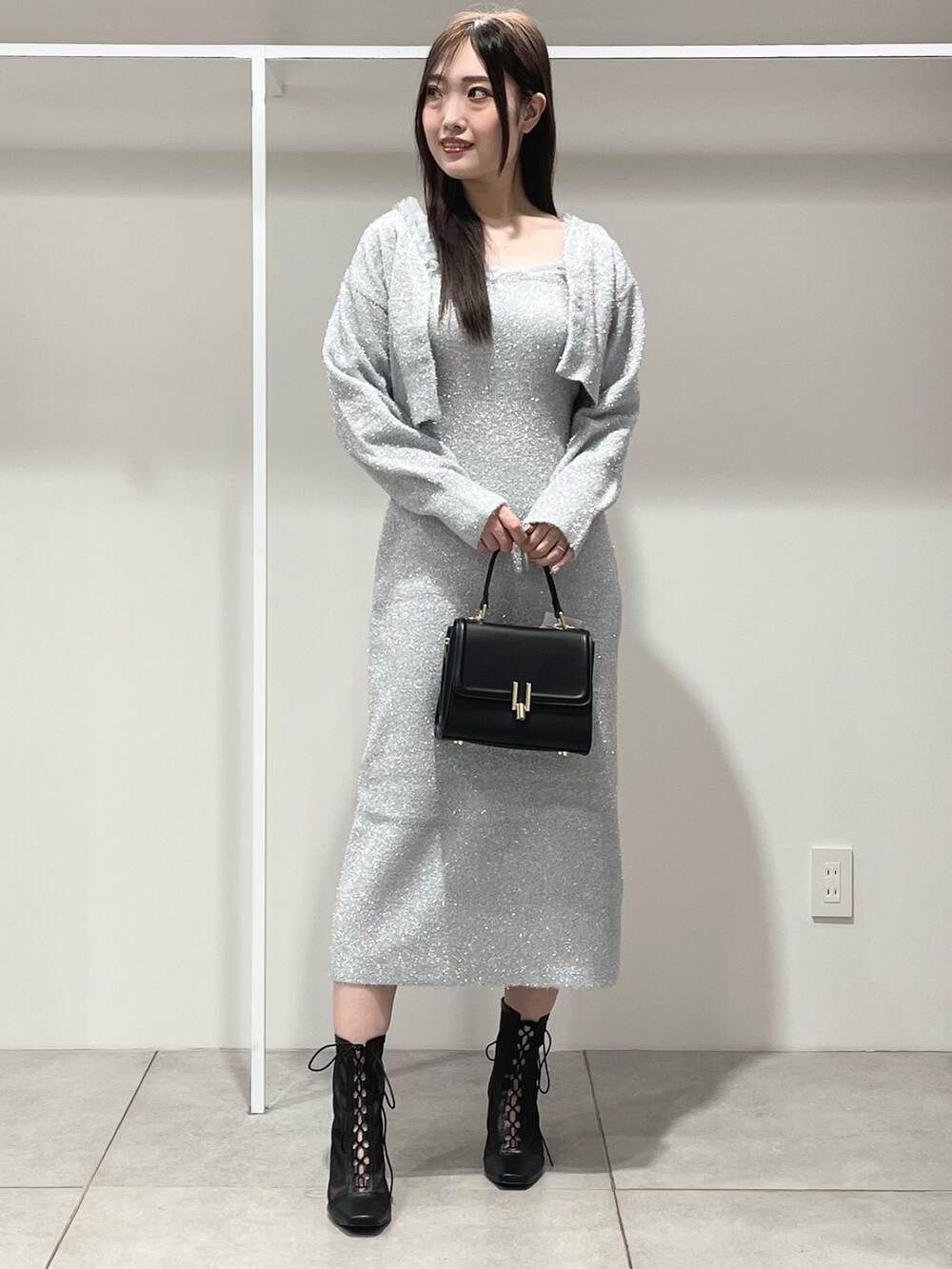 シルバー系のワンピース、ブラック系のショルダーバッグ、ブラック系のブーツを着用したレディースの秋コーディネートの2枚目の写真