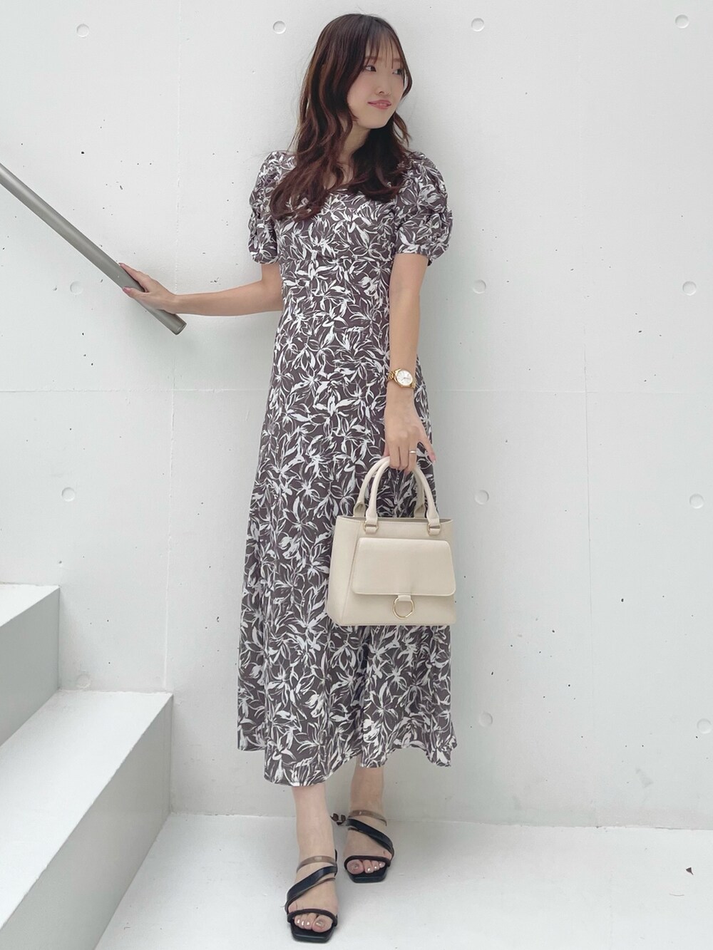 グレー系のワンピース、ブラック系のサンダル、ホワイト系のハンドバッグを着用したレディースの春コーディネートの4枚目の写真