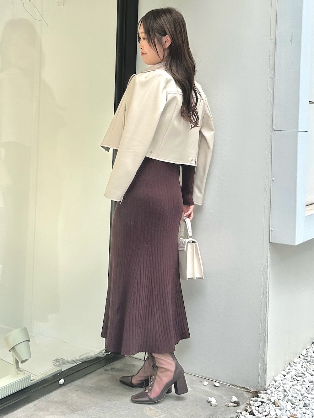 ホワイト系のライダースジャケット、ブラウン系のワンピース、ホワイト系のショルダーバッグを着用したレディースの夏コーディネートの2枚目の写真