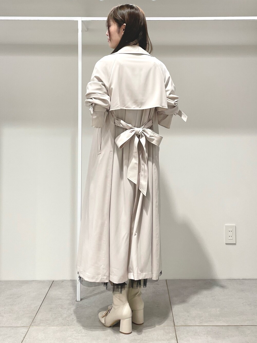 ベージュ系のワンピース、ピンク系のトレンチコート、ホワイト系のブーツを着用したレディースの春コーディネートの3枚目の写真