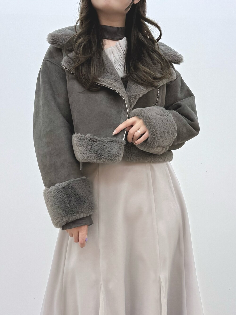 グレー系のスカート、ブラック系のブーツ、グレー系のムートンコートを着用したレディースの秋コーディネートの5枚目の写真