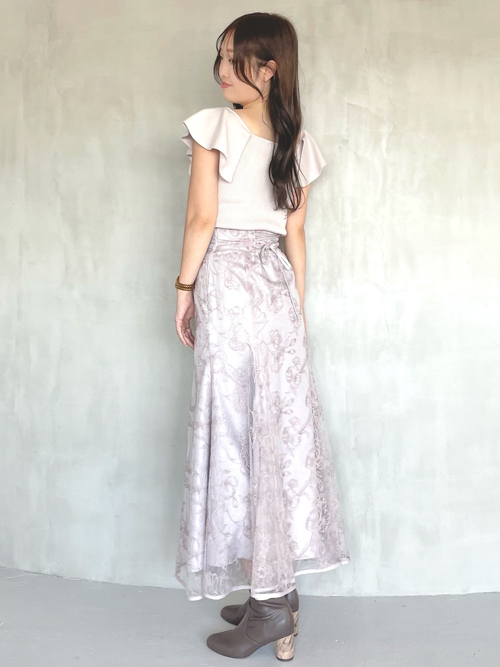 ピンク系のニット/セーター、ピンク系のスカート、ブラウン系のブーツを着用したレディースの春コーディネートの2枚目の写真