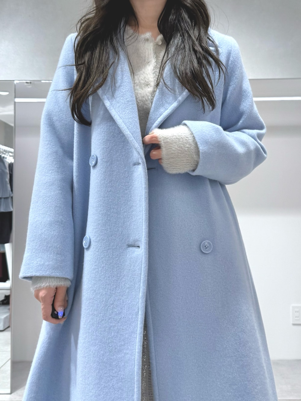 ブルー系のチェスターコート、ホワイト系のスカート、グレー系のカーディガン/ボレロを着用したレディースの秋コーディネートの5枚目の写真