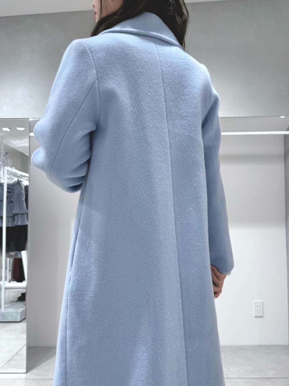 ブルー系のチェスターコート、ホワイト系のスカート、グレー系のカーディガン/ボレロを着用したレディースの秋コーディネートの6枚目の写真