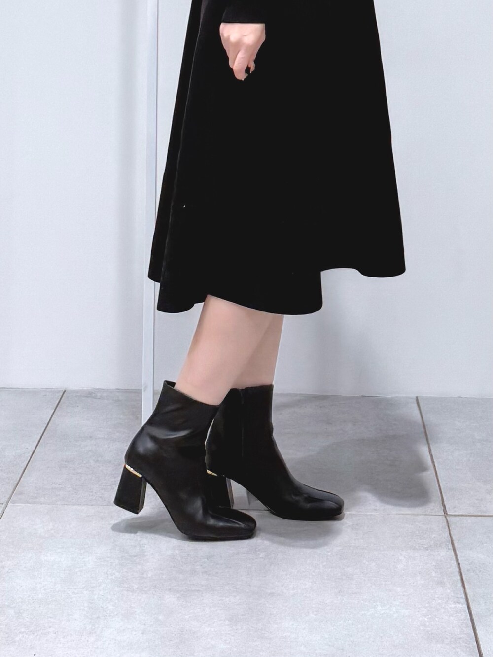 ホワイト系のハンドバッグ、ブラック系のブーツ、ブラック系のワンピースを着用したレディースの冬コーディネートの7枚目の写真