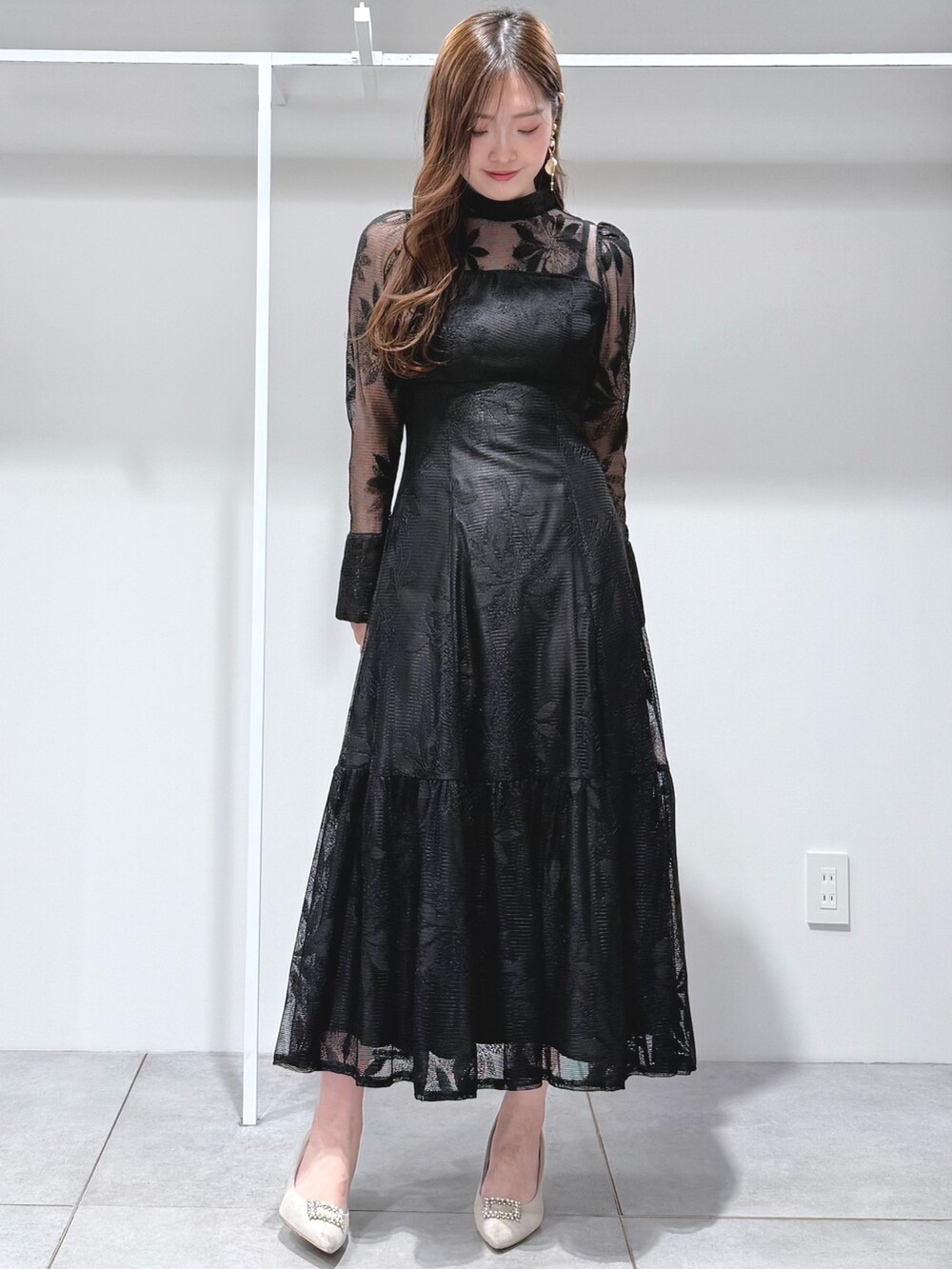 ブラック系のワンピース、ホワイト系のショルダーバッグ、ホワイト系のパンプスを着用したレディースの冬コーディネートの2枚目の写真