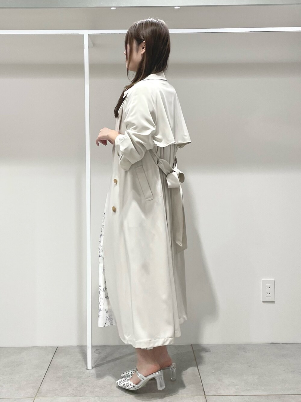 ホワイト系のトレンチコート、ホワイト系のワンピース、シルバー系のパンプスを着用したレディースの春コーディネートの2枚目の写真