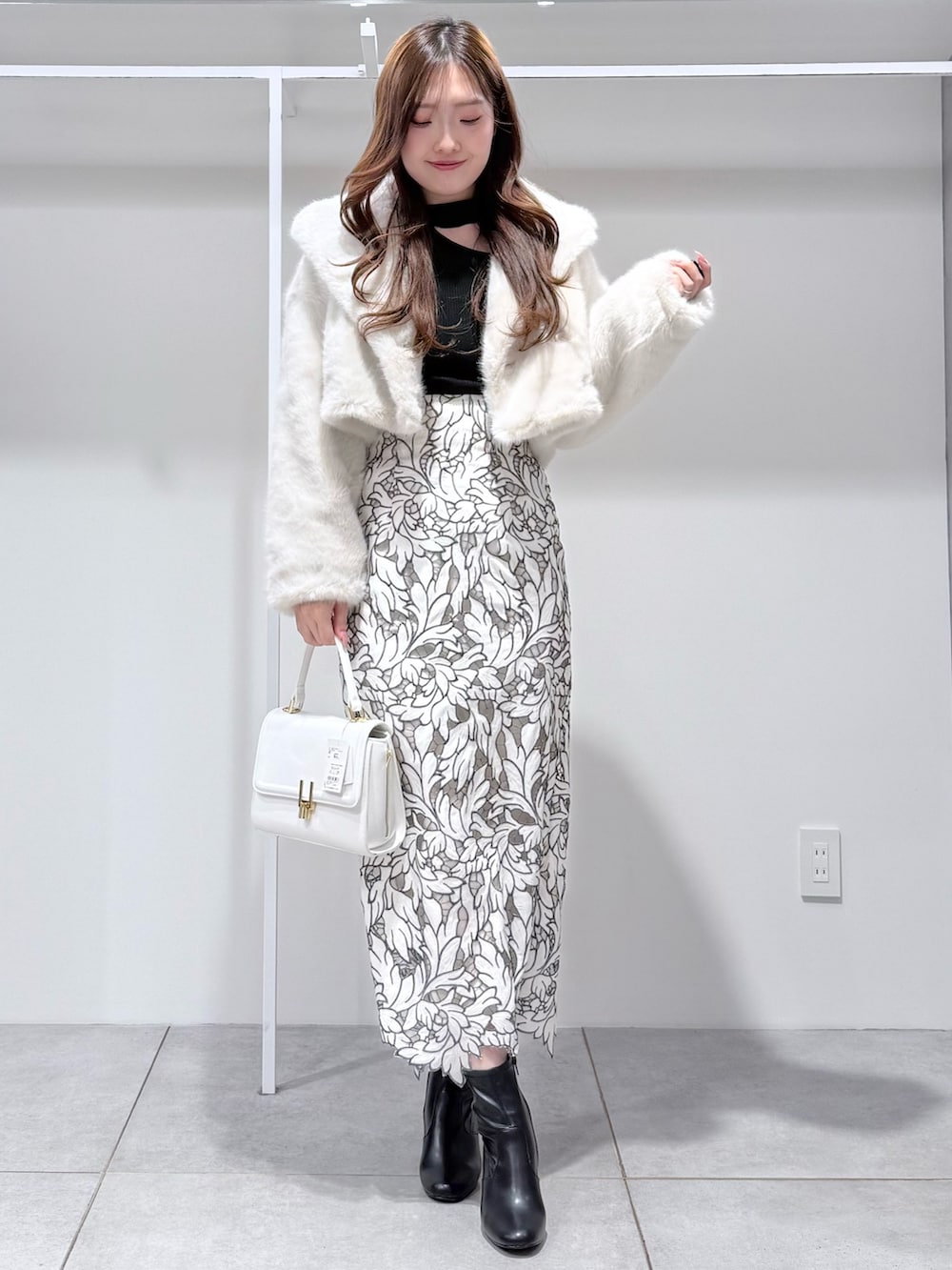 ホワイト系のその他アウター、ブラック系のブーツ、ホワイト系のハンドバッグを着用したレディースの冬コーディネートの2枚目の写真