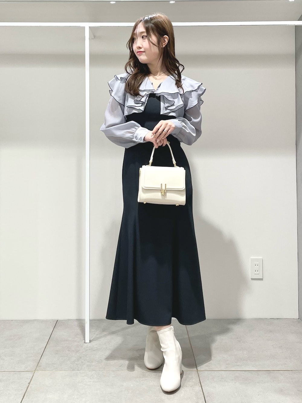 グレー系のワンピース、ホワイト系のブーツ、ホワイト系のハンドバッグを着用したレディースの冬コーディネートの2枚目の写真