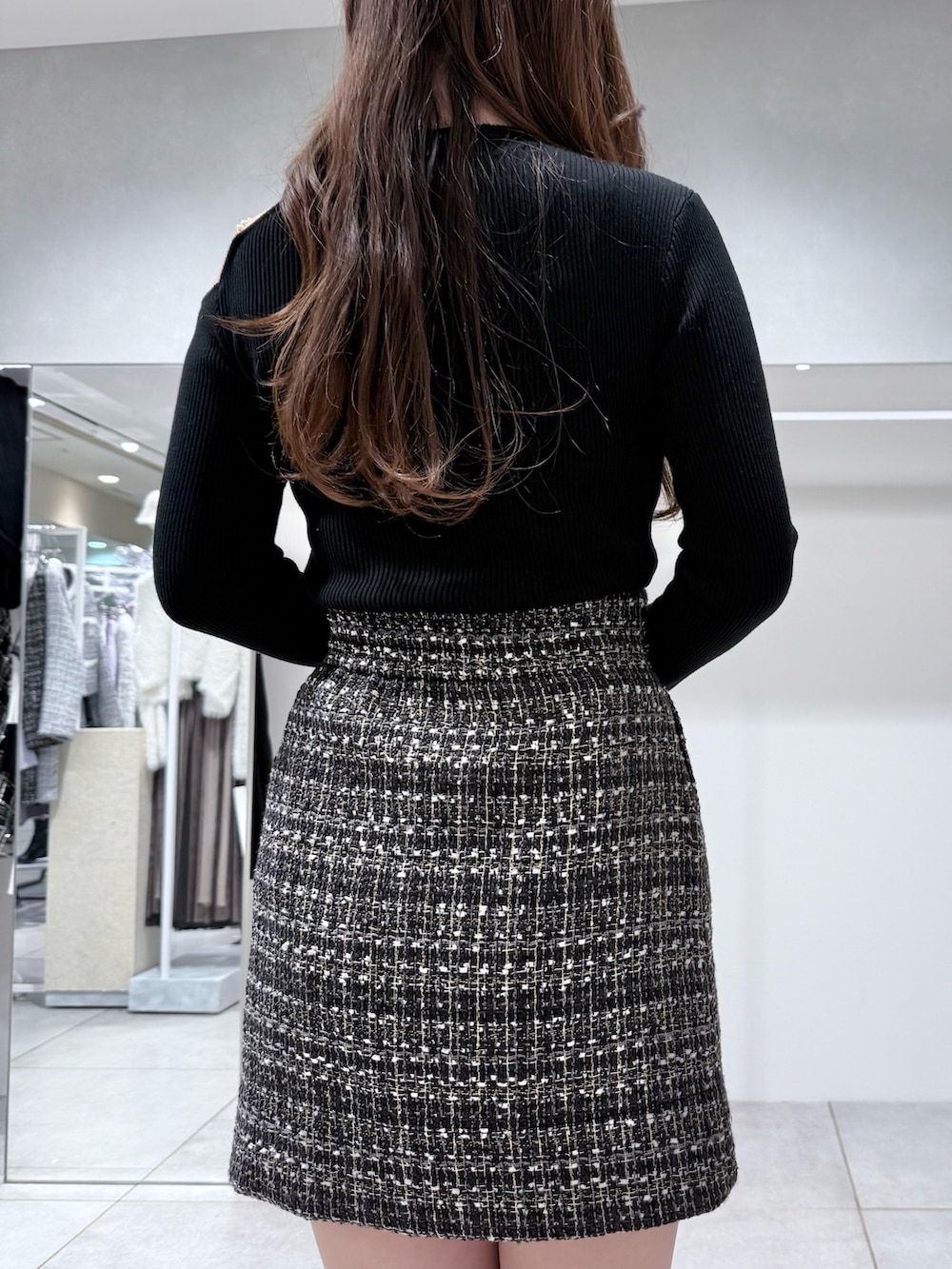 ブラック系のニット/セーター、ブラック系のスカート、ホワイト系のハンドバッグを着用したレディースの冬コーディネートの7枚目の写真