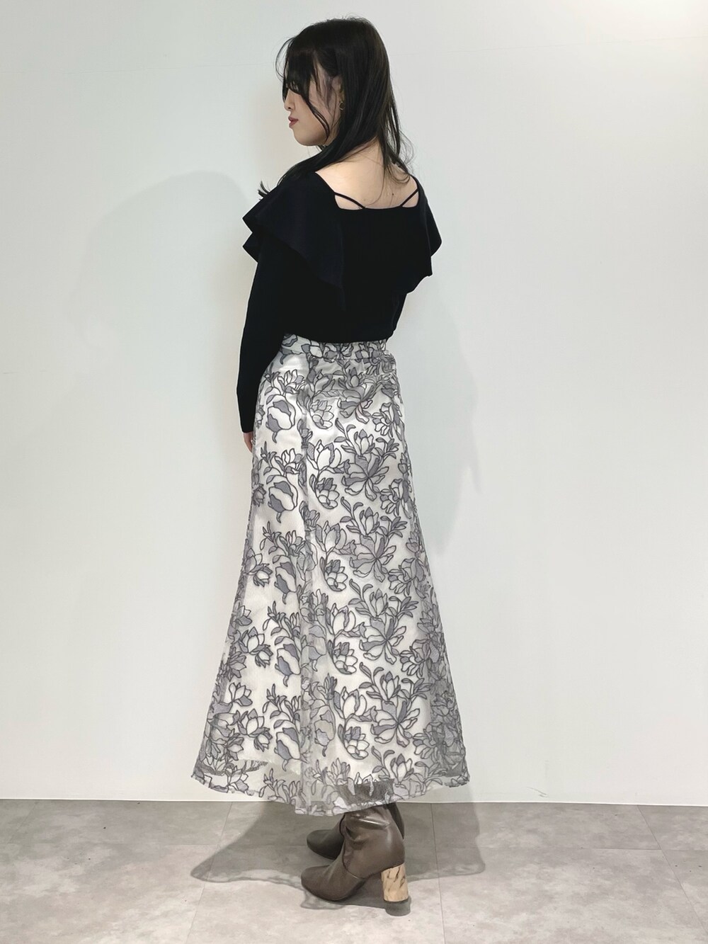 グレー系のスカート、ブラウン系のブーツ、ブラック系のダウンジャケット/コートを着用したレディースの冬コーディネートの8枚目の写真