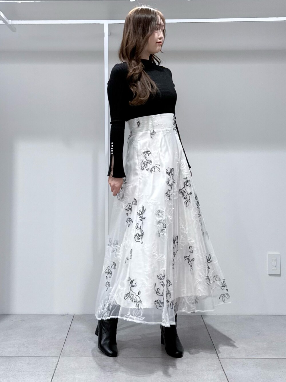 ブラック系のニット/セーター、ホワイト系のスカート、ブラック系のブーツを着用したレディースの冬コーディネートの3枚目の写真