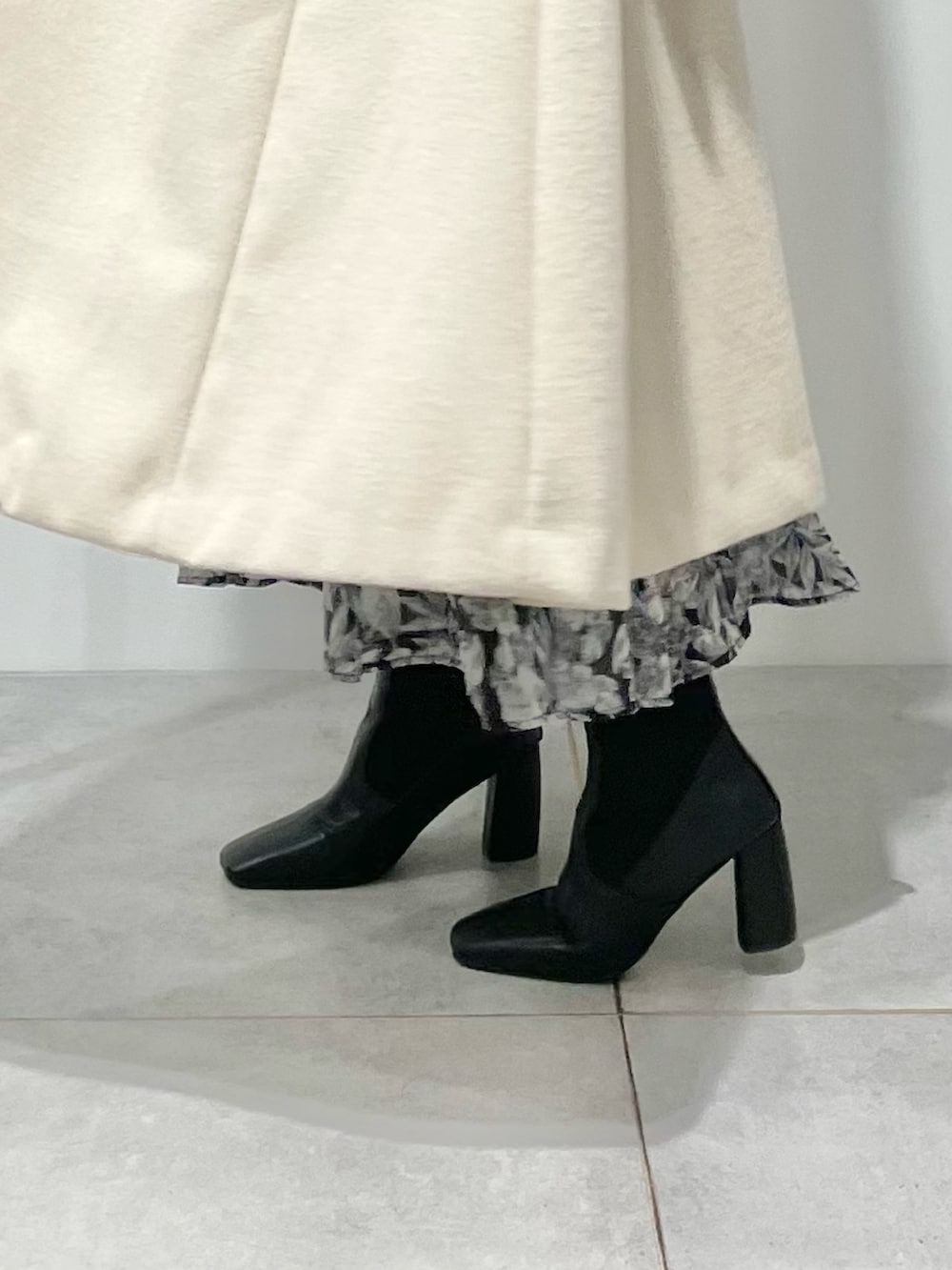 ベージュ系のチェスターコート、ブラック系のブーツ、ブラック系のスカートを着用したレディースの冬コーディネートの10枚目の写真