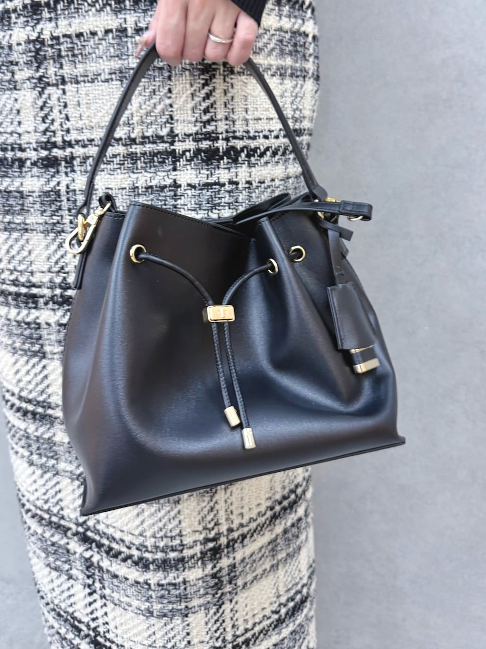 ブラック系のニット/セーター、ホワイト系のスカート、ブラック系のブーツを着用したレディースの冬コーディネートの7枚目の写真