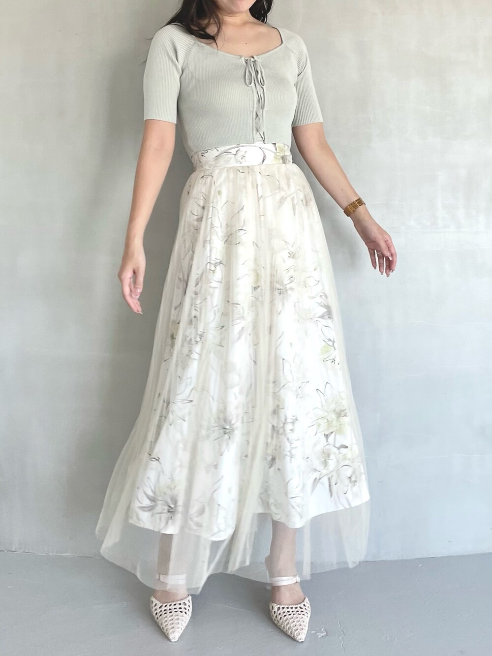 グリーン系のニット/セーター、イエロー系のスカート、ホワイト系のパンプスを着用したレディースの春コーディネートの2枚目の写真