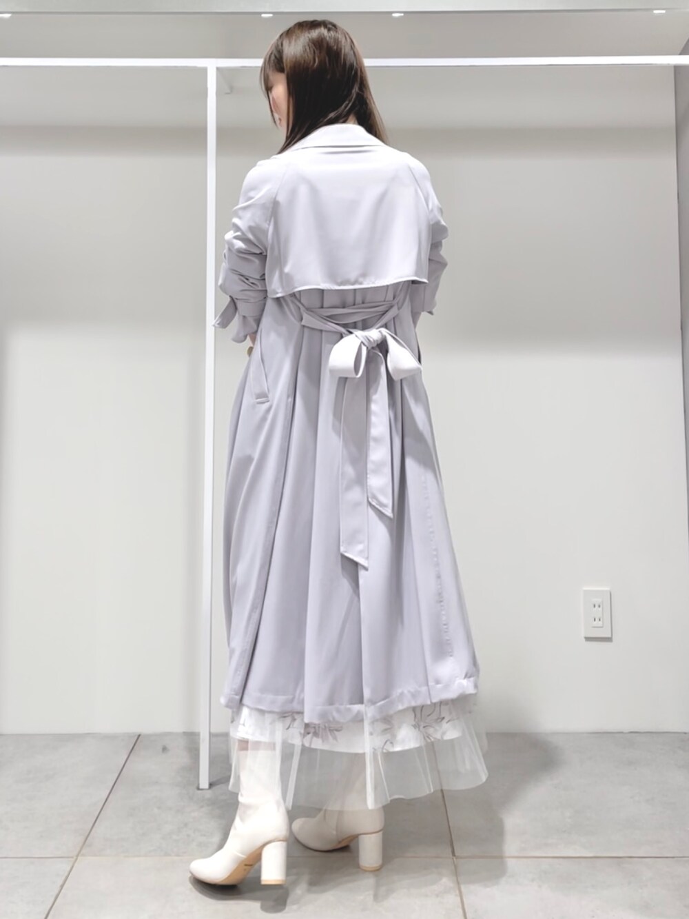 パープル系のトレンチコート、ホワイト系のニット/セーター、ピンク系のスカートを着用したレディースの春コーディネートの2枚目の写真