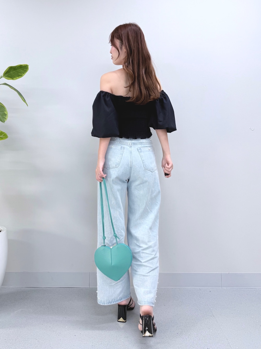 ブルー系のデニムパンツ、グリーン系のショルダーバッグ、ブラック系のサンダルを着用したレディースの夏コーディネートの3枚目の写真