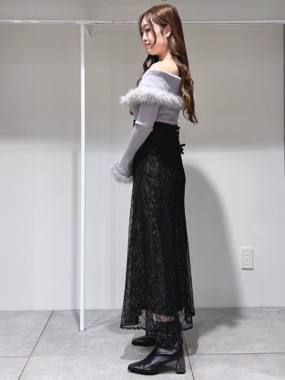 グレー系のニット/セーター、ブラック系のスカート、ブラック系のショルダーバッグを着用したレディースの冬コーディネートの2枚目の写真