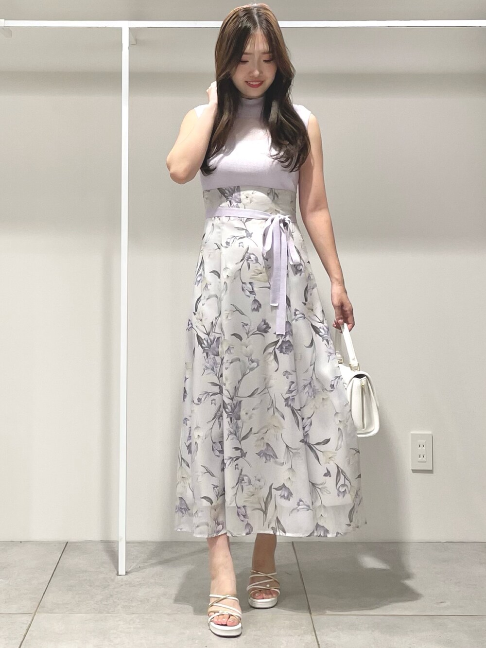 ホワイト系のハンドバッグ、ホワイト系のサンダル、パープル系のワンピースを着用したレディースの夏コーディネートの2枚目の写真