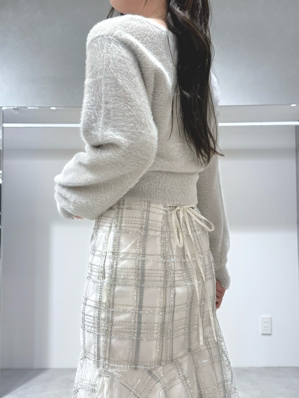 グレー系のカーディガン/ボレロ、ホワイト系のスカート、ホワイト系のブーツを着用したレディースの秋コーディネートの5枚目の写真