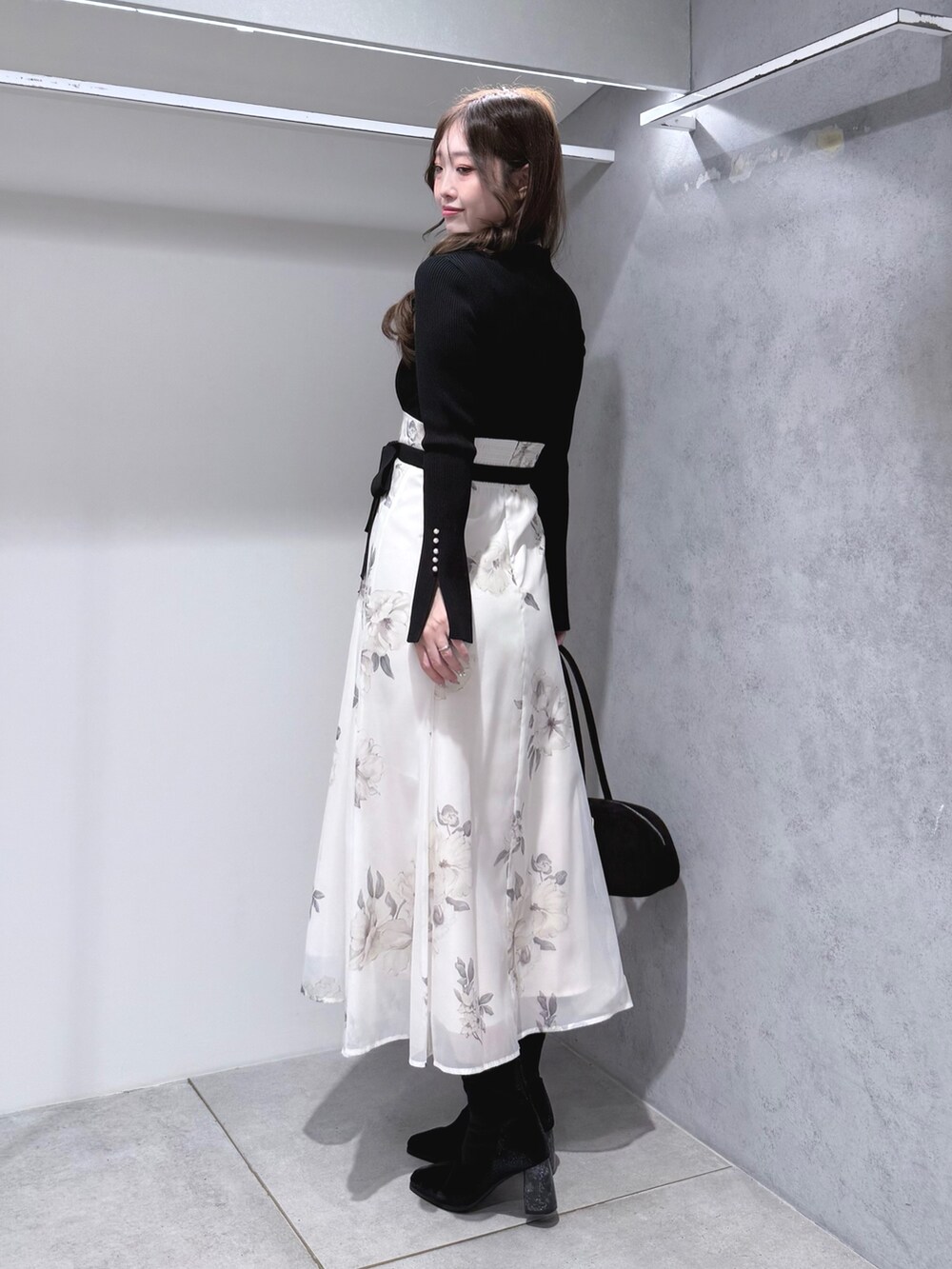 ブラック系のワンピース、ブラック系のブーツ、ブラック系のハンドバッグを着用したレディースの秋コーディネートの3枚目の写真