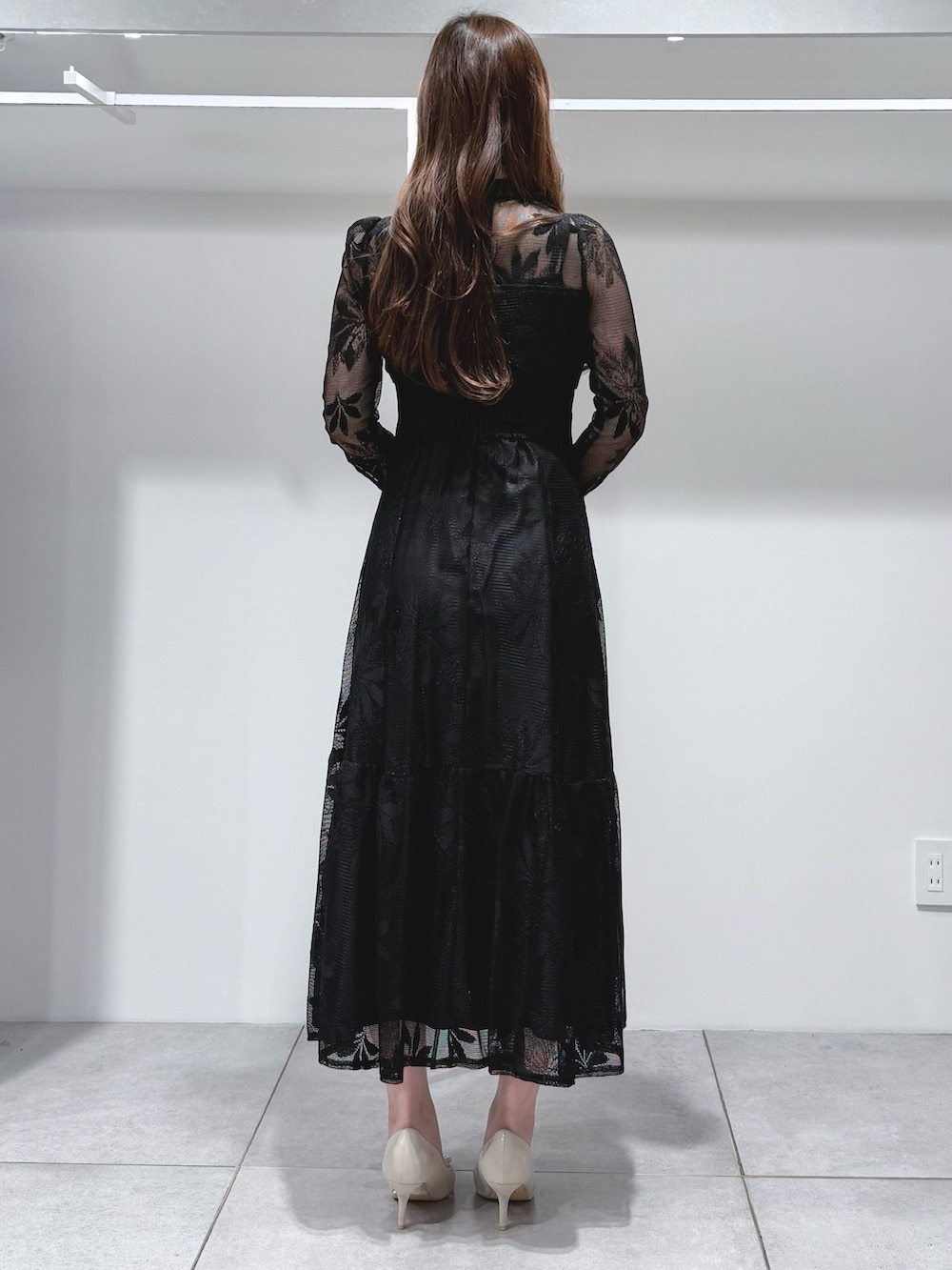 ブラック系のワンピース、ホワイト系のショルダーバッグ、ホワイト系のパンプスを着用したレディースの冬コーディネートの4枚目の写真