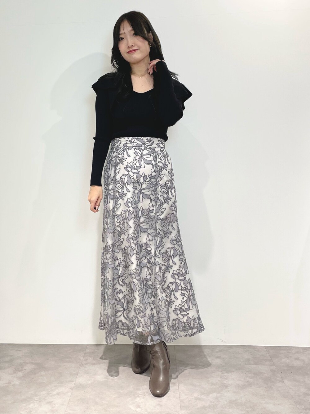 グレー系のスカート、ブラウン系のブーツ、ブラック系のダウンジャケット/コートを着用したレディースの冬コーディネートの7枚目の写真