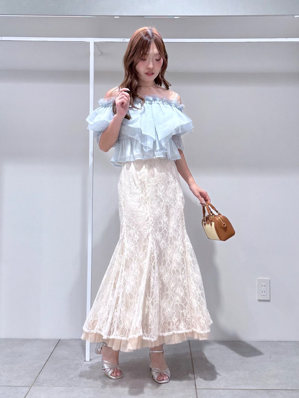 ブルー系のシャツ/ブラウス、ブラウン系のハンドバッグ、ホワイト系のスカートを着用したレディースの夏コーディネートの2枚目の写真