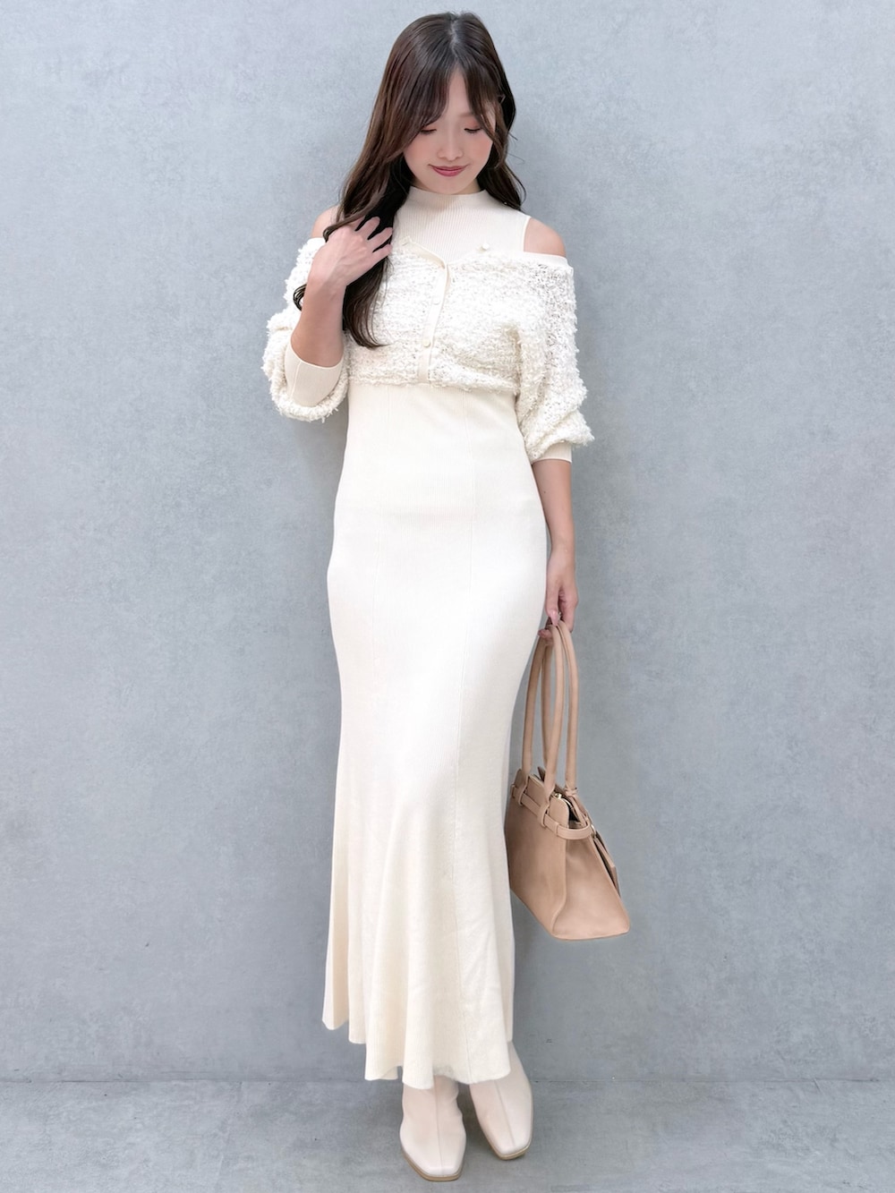 ホワイト系のワンピース、ホワイト系のブーツ、ベージュ系のハンドバッグを着用したレディースの秋コーディネートの2枚目の写真