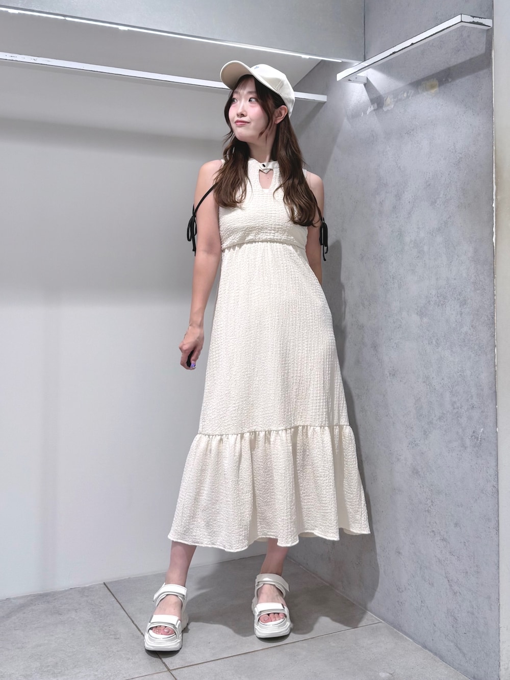 ホワイト系のワンピース、ホワイト系のサンダル、ホワイト系のキャップを着用したレディースの夏コーディネートの2枚目の写真