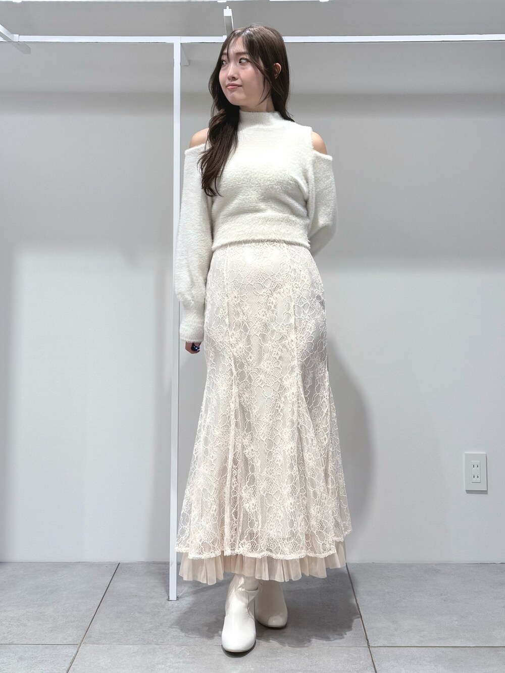 ホワイト系のニット/セーター、ホワイト系のスカート、ホワイト系のブーツを着用したレディースの秋コーディネートの2枚目の写真