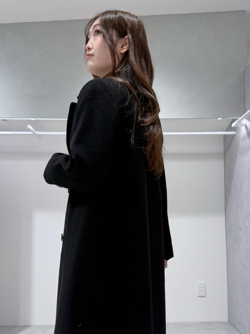 ブラック系のチェスターコート、ブラック系のニット/セーター、ブルー系のスカートを着用したレディースの冬コーディネートの6枚目の写真