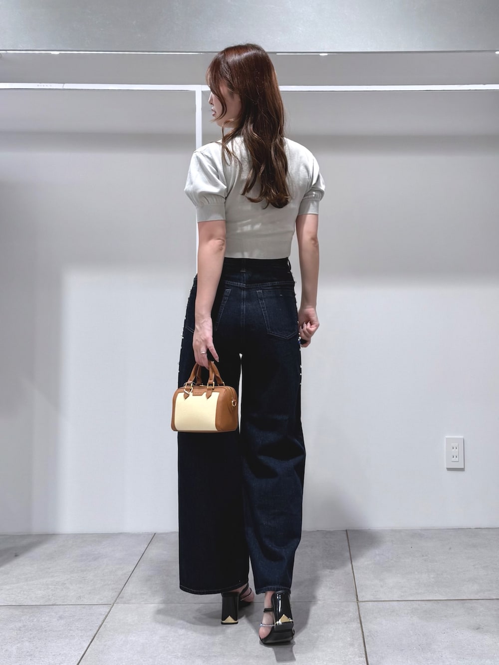 グリーン系のニット/セーター、ブルー系のデニムパンツ、ブラウン系のハンドバッグを着用したレディースの夏コーディネートの3枚目の写真