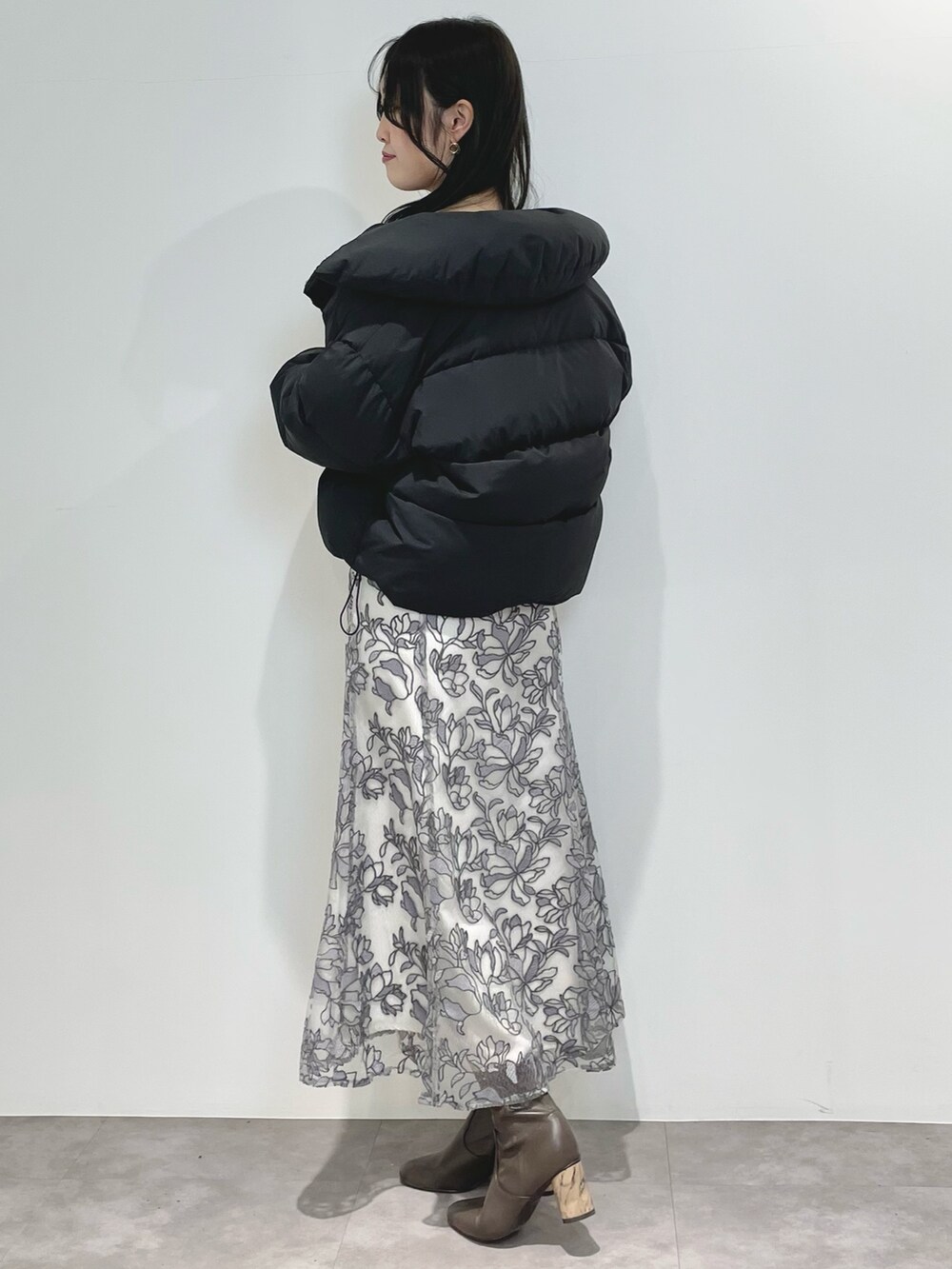 グレー系のスカート、ブラウン系のブーツ、ブラック系のダウンジャケット/コートを着用したレディースの冬コーディネートの3枚目の写真