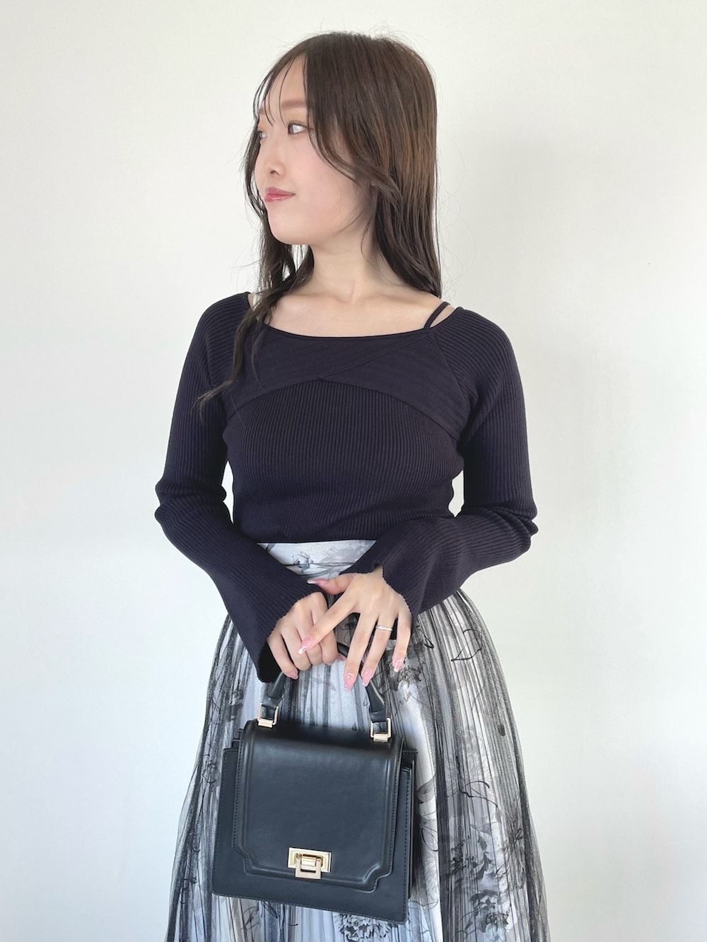 ブラック系のブーツ、ブラック系のスカート、ブラック系のハンドバッグを着用したレディースの春コーディネートの6枚目の写真